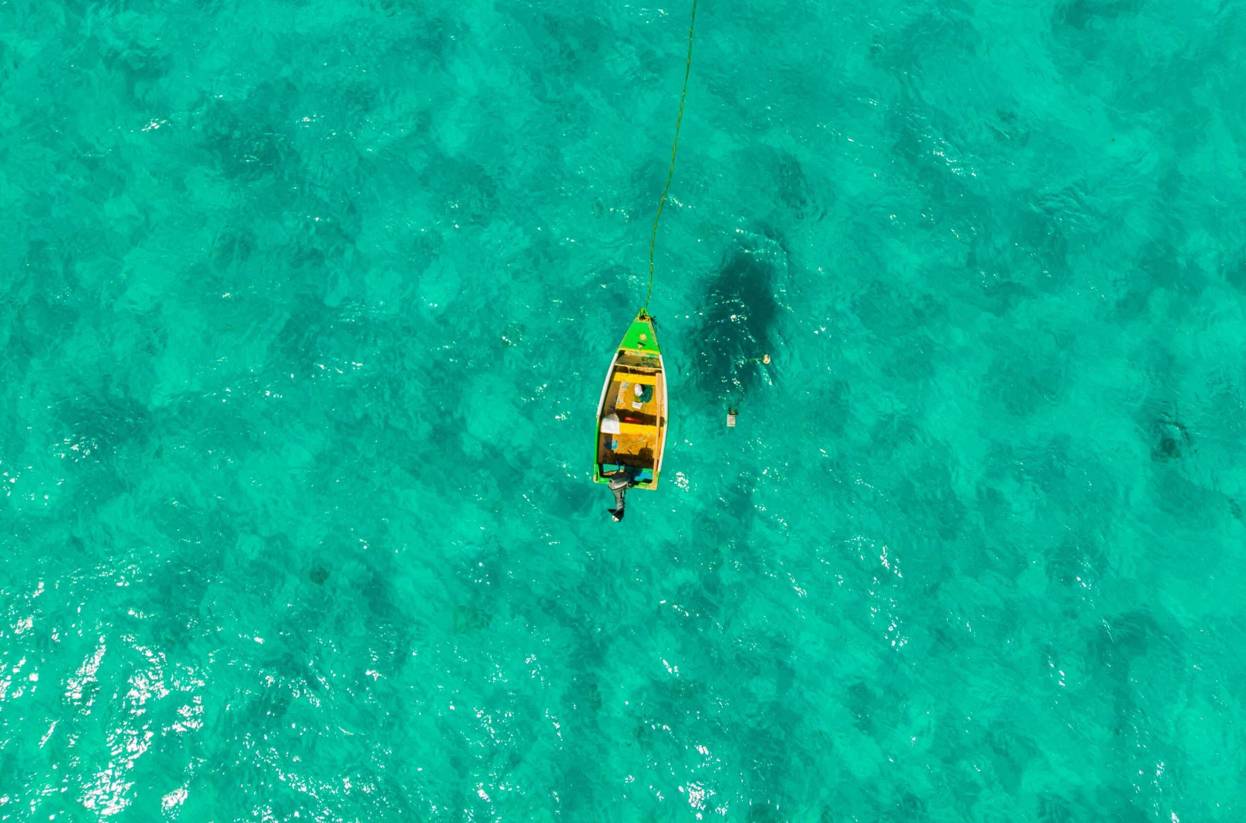 Drone capture of a lone boat sailing in the crystalline turquoise waters near Barbados.