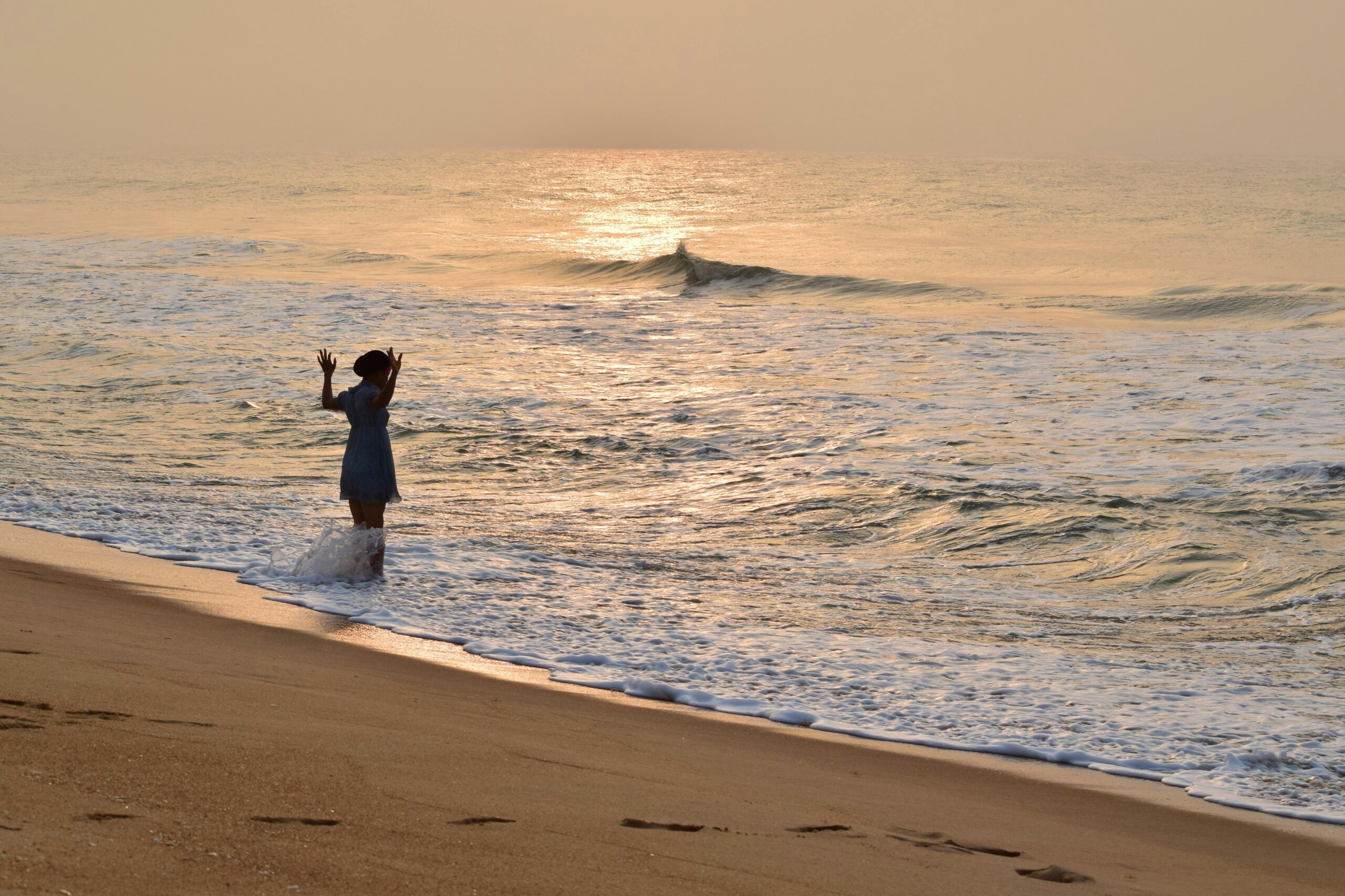 A person enjoys a tranquil moment at the sandy beach of Ouidah, Benin at sunset.