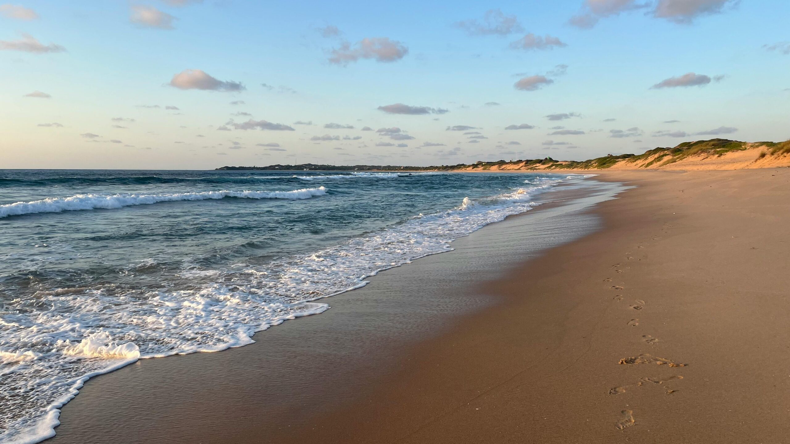 Serene sunset view of tranquil waves on Tofo Beach in Mozambique with soft golden sands.