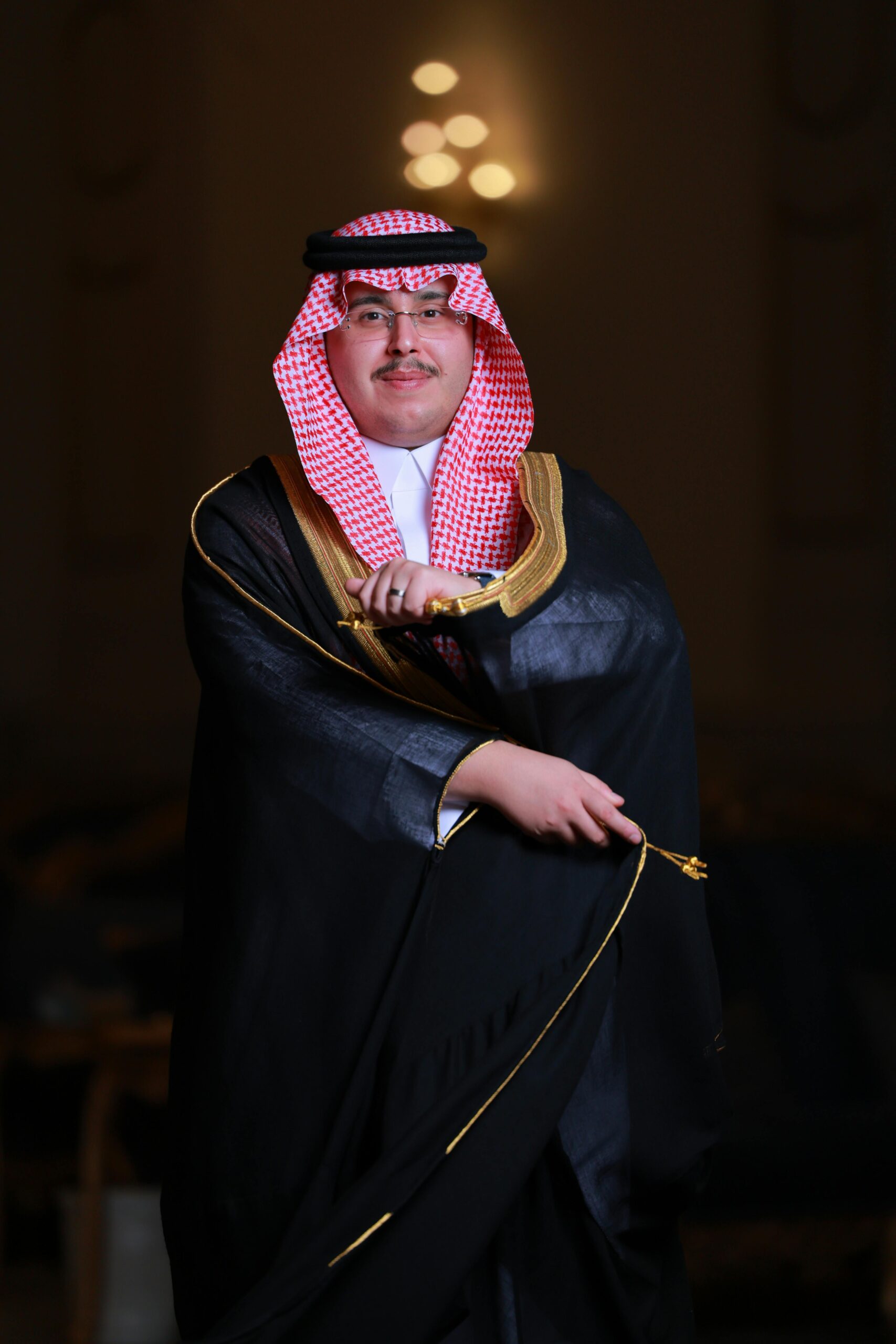 Elegant portrait of a man in traditional Middle Eastern attire with ornate sword.