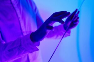 Close-up of hands interacting with a futuristic holographic glass interface in vibrant purple and blue lighting.